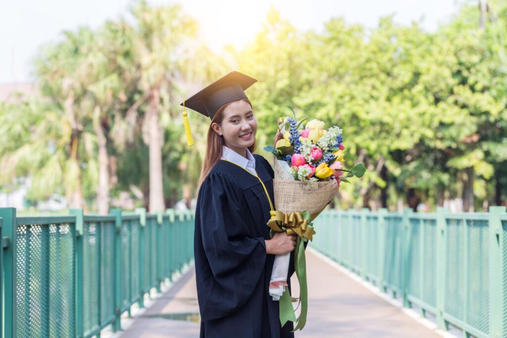 Mahasiswa memegang buket bunga wisuda sebagai pelengkap sesi foto graduation yang elegan.
