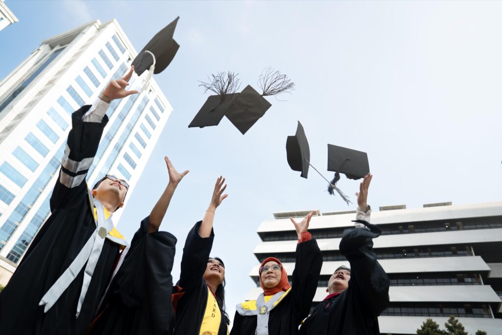 Mahasiswa memegang topi wisuda saat sesi foto graduation.